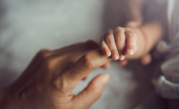 Mano de bebe agarrando el dedo de su padre
